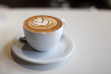 A warm and delicious Cappuccino in a simple white cup in a bistro or coffee bar