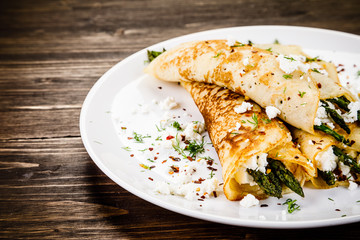 Crepes with spinach and cottage cheese on wooden background 