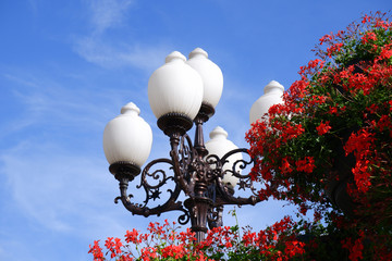Head of a decorative style lamppost against a blue sky 