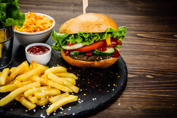 Tasty burger with chips served on stone plate 