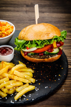 Tasty burger with chips served on stone plate 