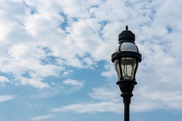Fototapeta na wymiar Street light isolated against cloudy blue sky background 