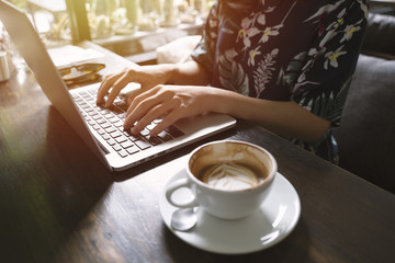 Hipster asian woman using laptop in the cafe with sunlight, lifestyle concept