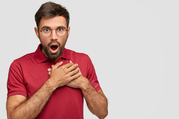 Emotional surprised male looks with bated breath, keeps mouth opened, terrific gaze can`t believe...