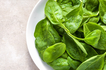Green leaves of spinach on plate, healthy diet, vegetarian food concept