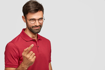Pleasant looking young unshaven guy with mysterious look, has pleased expression, intention to do...