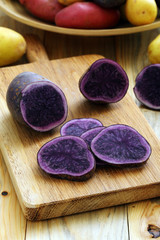 primo piano patate blu crude su sfondo tavolo di cucina