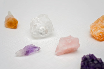 Healing crystals on a white table including: Amethyst Point and Cluster, Clear Quartz, Citrine, Calcite and Rose quartz. Gemstones are full of healing energy and good vibes.