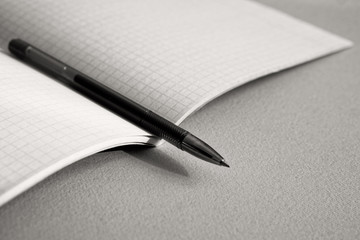 The pen lies on the notebook for mathematics. Monotone.