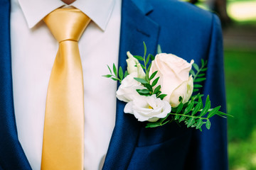 Groom in dark blue suit and yellow necktie wearing buttonhole bouquet