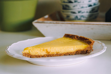 Piece of lemon tart on the white plate in the kitchen. Homemade dessert recipes 