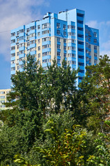 Obraz na płótnie Canvas New colored apartment houses, clear blue sky, green trees in bottom