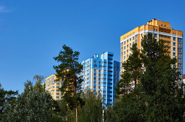 New colored apartment houses, clear blue sky, green trees in bottom