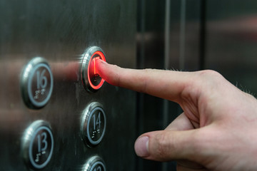 the man presses the elevator button with the red light.