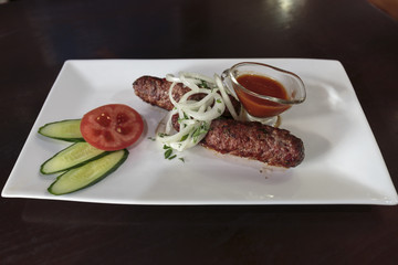 Lamb kebab meat roasted on the grill, served with sauce and onion. Middle Eastern food.
