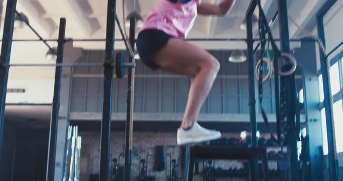 Young adult sporty Caucasian woman performing plyometric workout in functional gym, morning shot. 4K UHD 60 FPS SLOW MOTION