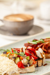 The concept of Italian cuisine, a tourist breakfast in a restaurant. different bruschetta on a long plate with a mug of coffee. Copy space, selective focus