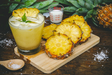 Pineapple juice and pineapple slices cut into pieces on a wooden table. Healthy wood fiber helps to...