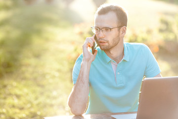 Young business man with glasses uses phone