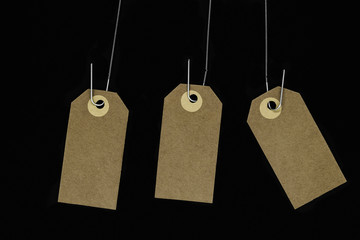 Hanging blank brown note cards with copy space hooked on metal spring and isolated on black background