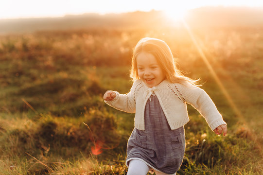 Portrait of a cute beatiful and happy girl running through the sunny field
