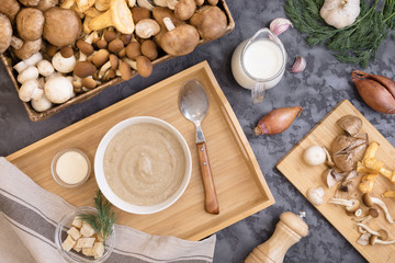 Mushroom cream soup with wild fungi, top view on dark textural background with fresh ingredients