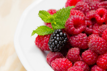 Red and delicious raspberries with mint in a white bowl