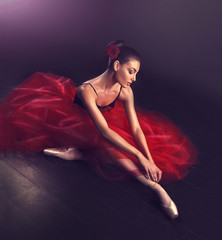 Ballerina. Young graceful woman ballet dancer, dressed in professional outfit, shoes and red weightless skirt is demonstrating dancing skill.   Beauty of classic ballet dance.   