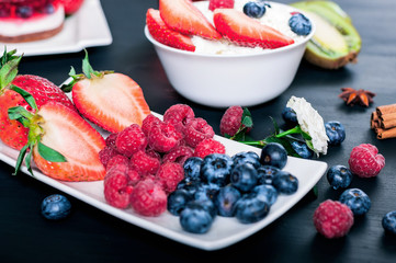 Berries of strawberries, blueberries and raspberries on a white saucer, proper nutrition, cottage cheese with berries