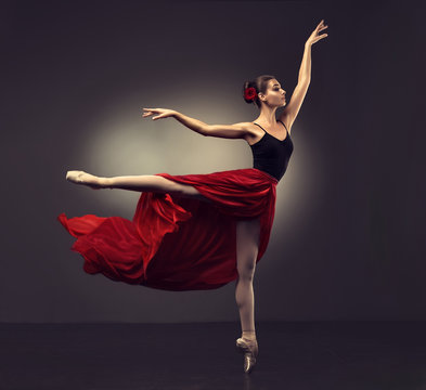Fototapeta Ballerina. Young graceful woman ballet dancer, dressed in professional outfit, shoes and red weightless skirt is demonstrating dancing skill.   Beauty of classic ballet dance.   