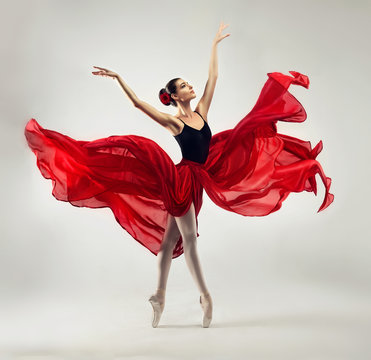 Ballerina. Young graceful woman ballet dancer, dressed in professional outfit, shoes and red weightless skirt is demonstrating dancing skill. 
Beauty of classic ballet dance. 
