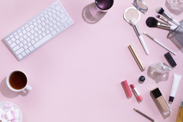 Makeup products and coffee or tea cup on pink color background with hard light and shadows, flat lay and top view