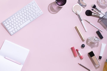 Top view of woman beauty blogger working desk with computer or laptop, notebook, decorative cosmetic, leaves shadows and hard light, envelope on pink and white pastel table. Flat lay background.