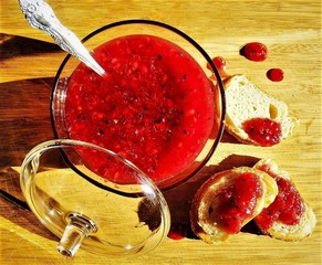 A Red jam with a transparent bowl with tosts on the wooden background