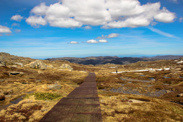 Footpath on top of the mountain in Australia with a bit of snow and blue sky and clouds