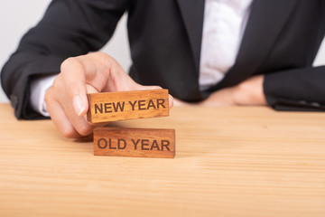 Hand of businesswoman choosing wood blog with icon and word New Year and Old Year