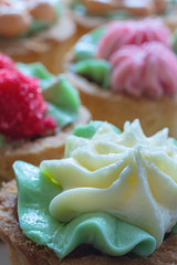 Close up view of a shortbread cakes with cream in the shape of flowers on top (shallow depth of field)