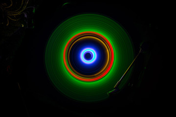 Music concept. Freezelight glowing vinyl on dark background or Turntable playing vinyl with glowing abstract lines concept on dark background.