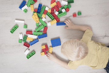 Blond boy lies on the floor among the constructor. Top view
