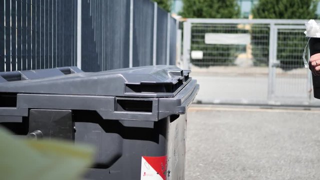 Hand of man throwing away mixed garbage in big waste container for recycling