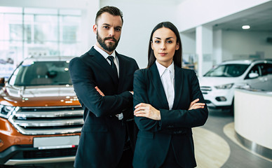 Super salesteam in dealership, two consultants or managers in black full suit with crossed arms...