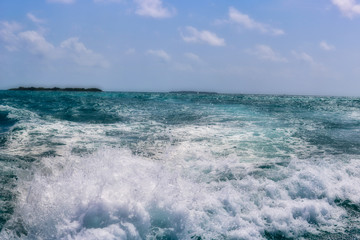 Obraz premium dieses einzigartige bild zeigt wie das wasser vom bootsmotor spritzt und im hintergrund sieht man eine maledivische insel