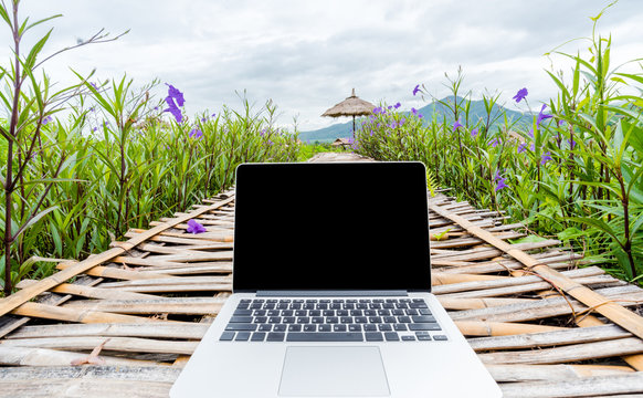 Laptop with blank screen on wooden road in nature outdoor park