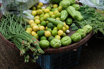 Green vegetables selling in round rattan tray on the ground at street market