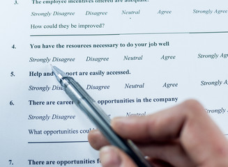 Respondent holding a pan in a hand and answeing questions in employee survey. Questions relating to managerial practices, corporate culture, career growth, and professional relationships. Close-up