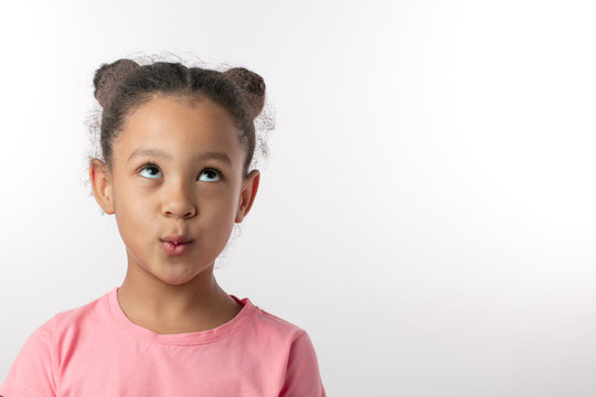 whistlying girl looking up.indifference concept.close up portrait. isolated white background. copy space. kid is ignoring parents, friends.lie and falsehood concept