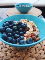 Healthy breakfast in a blue bowl. Oatmeal with blueberries and nut mix. Healthy food concept. Top view, side view. Space for text.