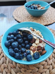 Healthy breakfast in a blue bowl. Oatmeal with blueberries and nut mix. Healthy food concept. Top view, side view. Space for text.
