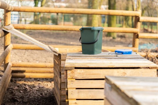 Green bucket bin on wooden compost heap 