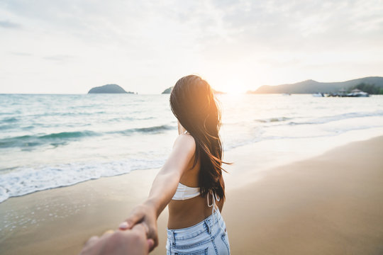 Couple holding hands on beach in sunset